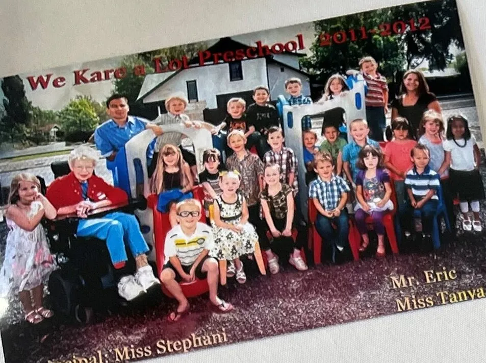 Group photo of preschool children and teachers from We Kare a Lot Preschool, school year 2011-2012, outdoors with play equipment and a house in the background